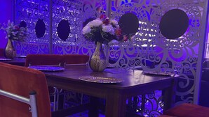 A dining area with a wooden table, red upholstered chairs, and a decorative wall with intricate patterns. - Farik Hotels and Suites  (Ibadan)