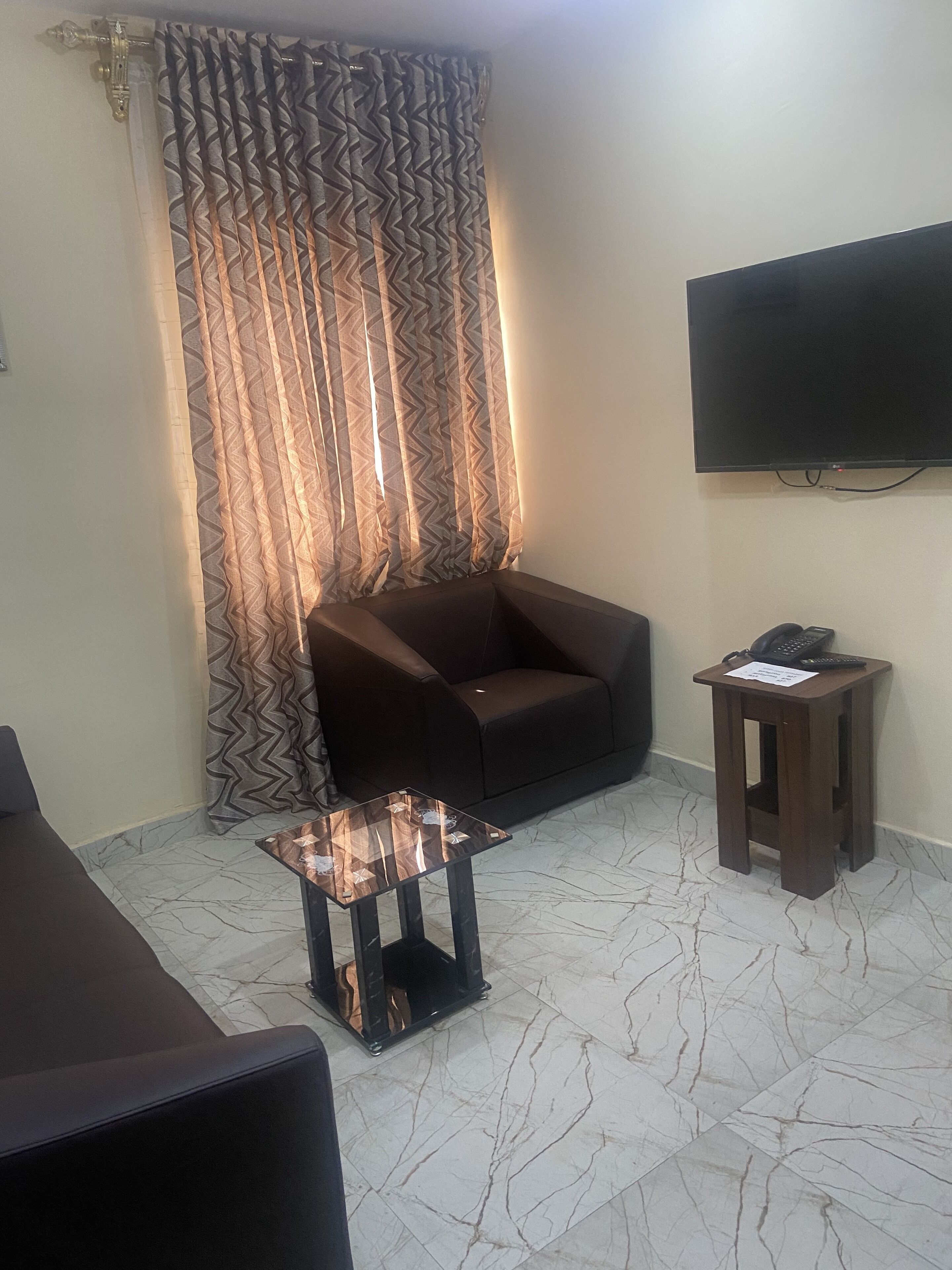 A living room with a sofa, a coffee table, a TV, and a patterned curtain.