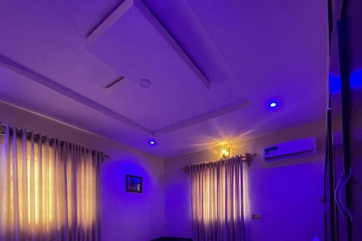 A bedroom with a bed, curtains, and a nightstand.