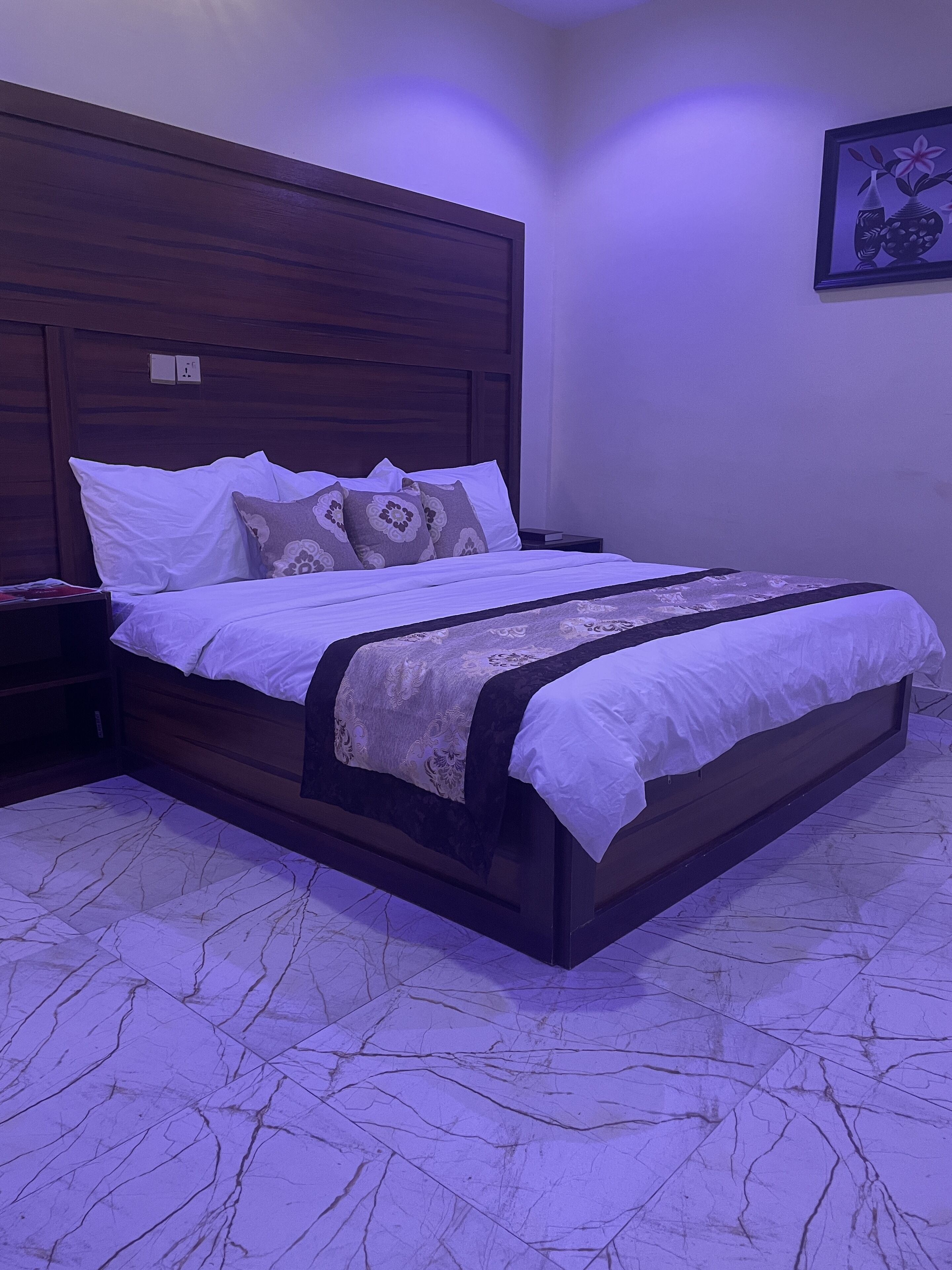 A neatly made bed with a wooden headboard, white bedding, and decorative pillows.