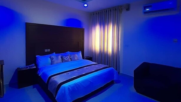 A modern bedroom with a large bed, a headboard, and a ceiling light. - Farik Hotels and Suites  (Ibadan)