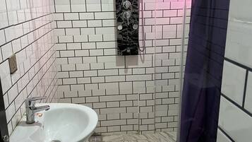 A bathroom with white and black patterned tiles, a white sink, a shower with a glass door, and a toilet.