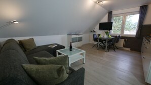 Una sala de estar moderna con un sofá, una mesa de centro de vidrio y una zona de comedor con una mesa y sillas.