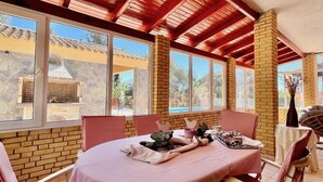 Un espace repas avec un mur en briques, de grandes fenêtres et un plafond en bois.