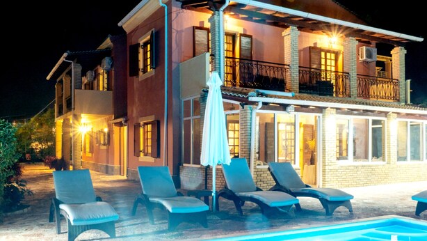 Une maison à deux étages avec une piscine, un espace salon extérieur et un balcon.