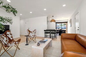 Een moderne woonkamer met een leren bank, een salontafel en een eethoek met een tafel en stoelen.
