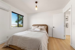 A bedroom with a bed, a window with a view, a door, and a light fixture.