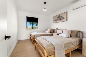 Een slaapkamer met twee houten bedden, een raam met uitzicht en een plafondlamp.