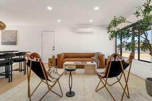 Een moderne woonkamer met een bank, twee stoelen, een salontafel en een eethoek.