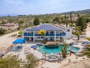 Une grande maison à deux étages dotée d’une piscine, de panneaux solaires et offrant une vue sur le paysage environnant.