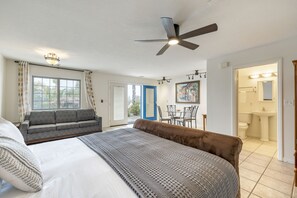 Une chambre à coucher avec un grand lit, un canapé, une table à manger et une salle de bain visible à travers une porte ouverte.
