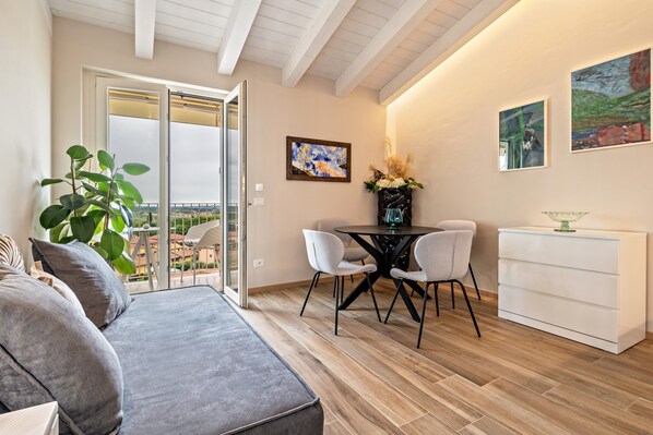 Un salon moderne comprenant un canapé, une table à manger avec des chaises, un meuble blanc et des œuvres d’art accrochées aux murs.