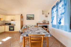Una cocina con una mesa de comedor, sillas y un ventanal con cortinas azules.