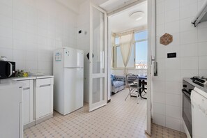 Una cucina compatta con frigorifero, forno a microonde e un piccolo angolo ristoro con tavolo e sedie.