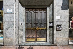 A building entrance with a metal gate, a telephone, and a sign indicating 'DIVINA APARTMENTS'.