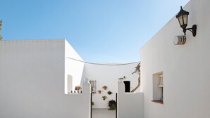 A narrow alleyway with white walls, a black lamp, and potted plants.