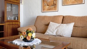 A living room with a glass coffee table, a sofa, and a cabinet with glass doors.