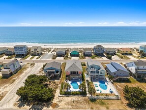 Un quartier résidentiel situé sur la côte, avec des maisons, une plage et un complexe de piscines.