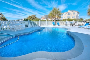 Relax by the pool surrounded by a white picket fence and lounge chairs.