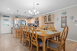 Une cuisine avec des meubles en bois, une table à manger avec des chaises et un lustre.