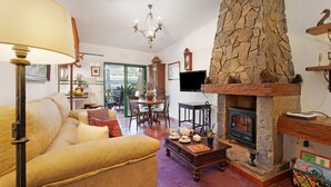 Una sala de estar acogedora con chimenea de piedra, un sofá, una mesa de centro con juego de té y un televisor.