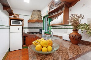 A kitchen with a microwave, refrigerator, sink, and a bowl of lemons on the counter.