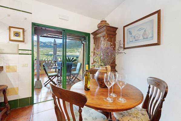A dining area with a table, chairs, a wine bottle, and glasses.