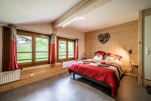 Un dormitorio con cama, paredes de madera, una ventana con cortinas y una decoración con forma de corazón en la pared.