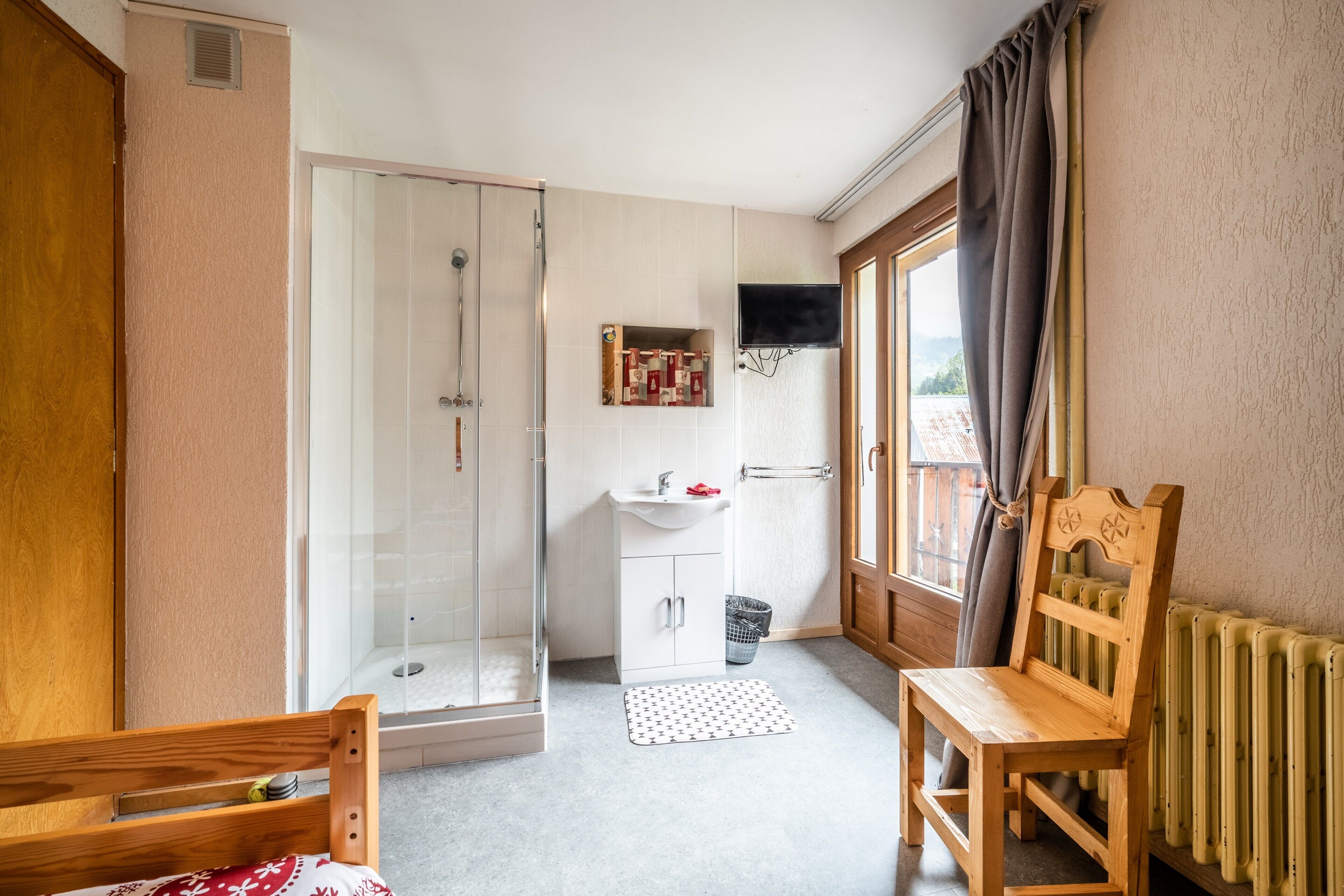 Baño con ducha, lavamanos y ventana con cortinas.