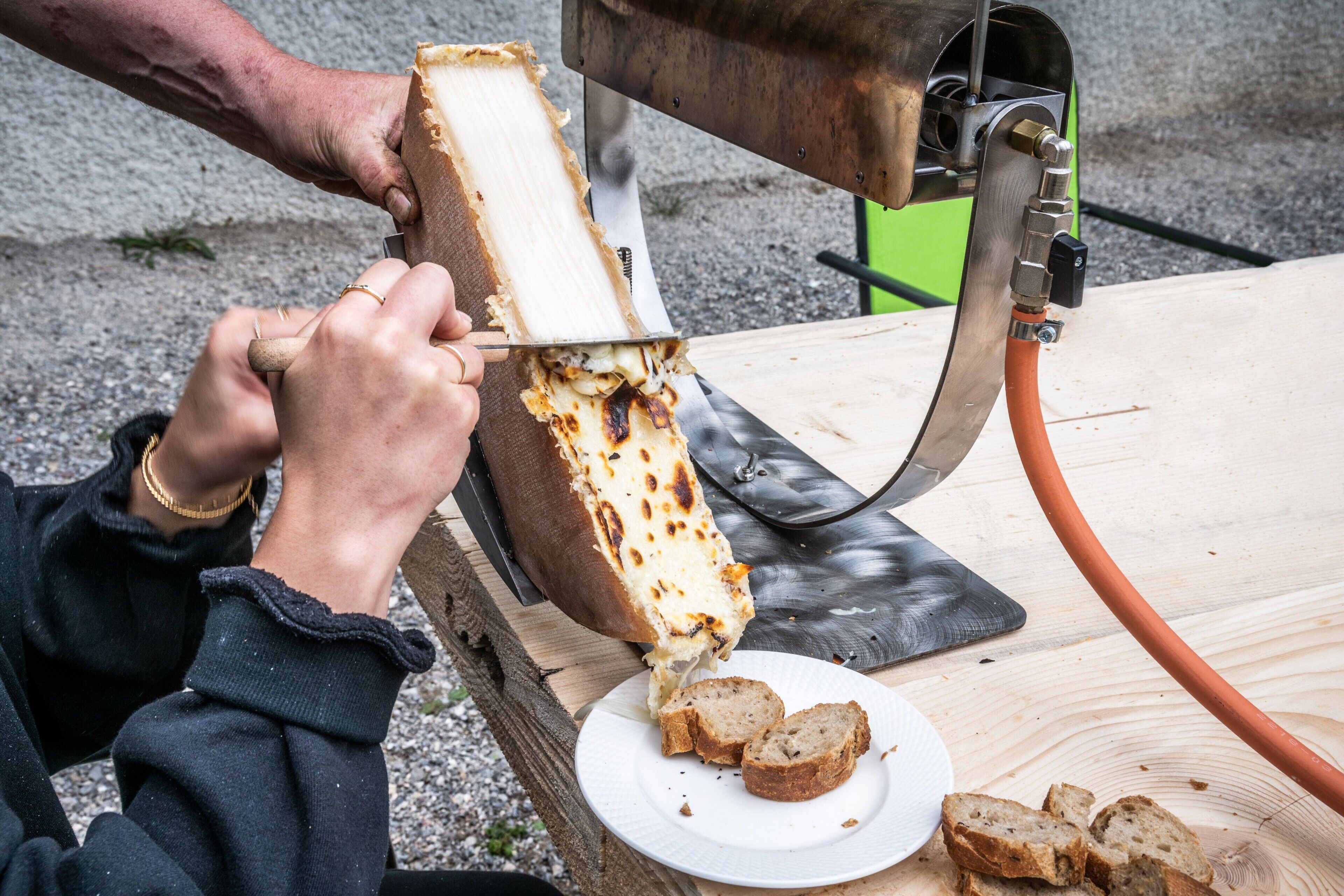 Une personne qui tranche une miche de pain sur une table en bois.