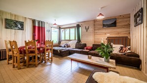 A wooden-paneled room with a dining table, chairs, a sofa, and a coffee table. - Apartment 'Coeur De Charmy' with Mountain Views and Wellness Spa (Abondance)