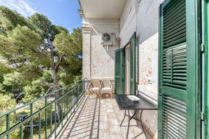 A balcony with a table and chairs, a green railing, and a building with a white facade and green shutters. - Villa 'Luisa' with Sea View, Wi-Fi, and Air Conditioning (Leuca)