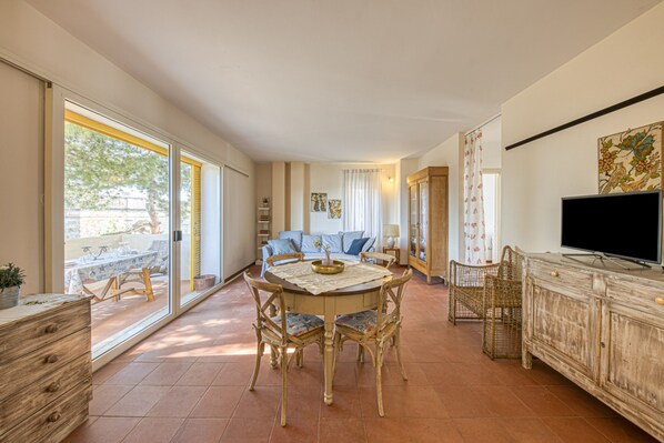 A spacious living area with a dining table, chairs, a television, and a sofa.