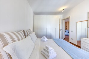 A bedroom with a bed, a bedside table, a wardrobe, and a mirror.