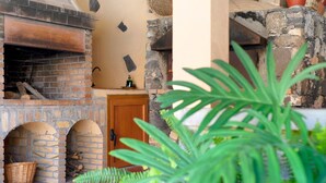 A brick fireplace with a wooden door, stone walls, and a basket of firewood.