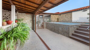 A stone exterior wall, a wooden ceiling, a stone pool, and a staircase.