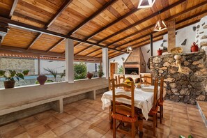An outdoor dining area with a stone fireplace, wooden ceiling, and potted plants. - Holiday Home "Casa Las Toscas" with Mountain Views, Pool and Wi-Fi (Ingenio)