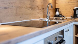 Une cuisine moderne avec un revêtement mural en bois, un évier en acier inoxydable et une machine à café.