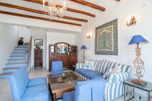 Ein Wohnzimmer mit Treppe, einem Sofa, einem Couchtisch und einer Deckenleuchte.