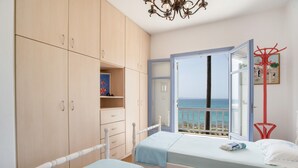 A bedroom with two beds, a wardrobe, and a balcony with a view of the sea. - Vacation Home "On a Magnificent Sandy Beach" with Sea View, Terrace & Wi-Fi (Naxos)