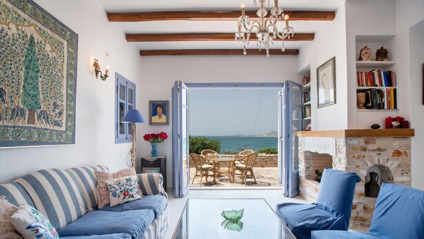 A living room with a sofa, chairs, a coffee table, a fireplace, and a view of the sea. - Vacation Home "On a Magnificent Sandy Beach" with Sea View, Terrace & Wi-Fi (Naxos)