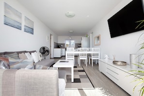 A modern living room with a sofa, coffee table, and dining area.