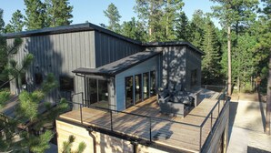 Ein modernes Haus mit Terrasse, großen Fenstern und Blick auf den umliegenden Wald.