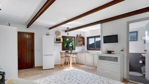 Un dormitorio con cama, techo de madera, cocina con comedor y baño.