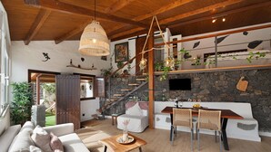 A cozy interior with a wooden ceiling, a stone fireplace, a dining area with a table and chairs, and a staircase with plants. - Holiday Home "Tajaraste 2" with Sea & Mountain Views, Private Terraces & Wi-Fi (Hermigua)