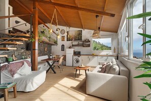 A spacious living area with a sofa, dining table, and kitchen area with a view. - Holiday Home "Tajaraste 2" with Sea & Mountain Views, Private Terraces & Wi-Fi (Hermigua)