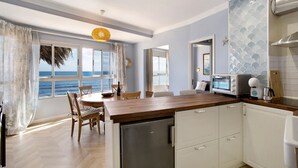 A kitchen with a wooden countertop, white cabinets, a built-in oven, and a view of the sea through large windows. - Vacation Apartment 'Ocean Side Arinaga' with Sea View and Wi-Fi (Arinaga)
