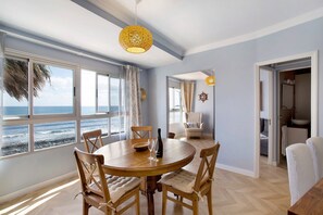 Un comedor con vistas al océano, una mesa redonda de madera y sillas.