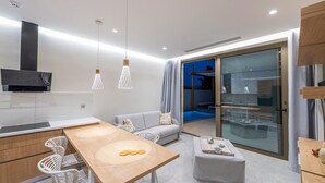 A modern kitchen with a dining area, a sofa, and a glass door leading to a balcony. - Villa "Suite Erifilli" with Sea View, Private Pool & Wi-Fi (Meganisi)