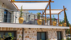 A balcony with outdoor seating, large planters, and a wooden pergola structure. - Villa "Suite Erifilli" with Sea View, Private Pool & Wi-Fi (Meganisi)